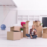 woman with many cardboard boxes sitting on floor